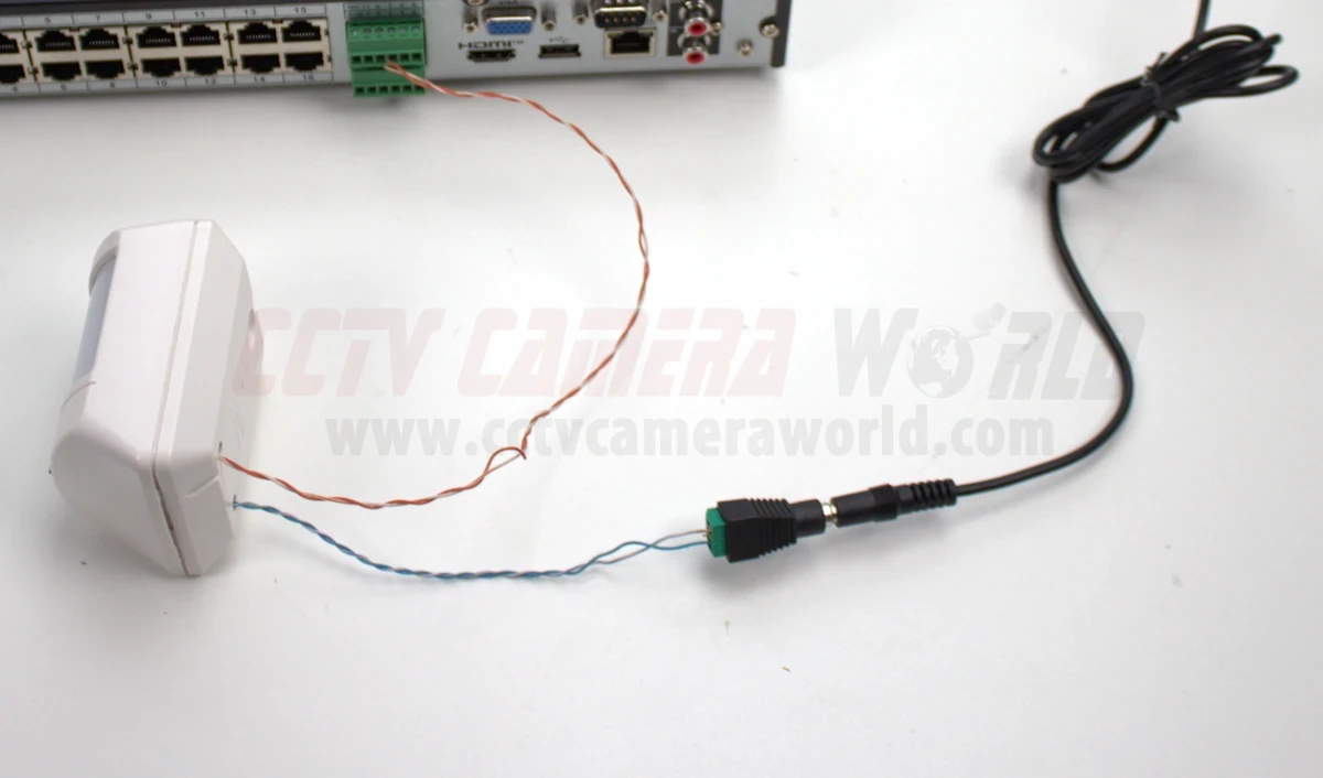 A externally powered PIR sensor wired into the alarm input block of an NVR