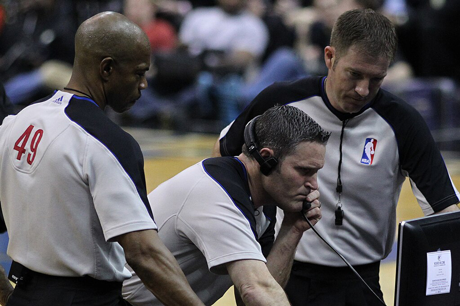 NBA coaches reviewing footage on a screen